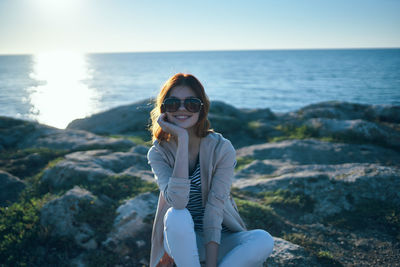 Portrait of smiling young woman by sea against sky