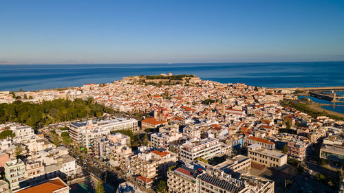 High angle view of townscape by sea against clear sky