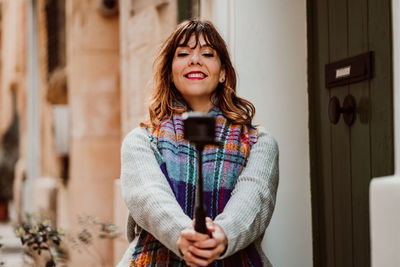 Woman holding monopod standing in alley