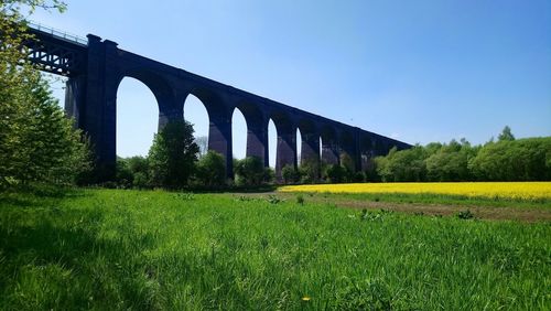 Arch bridge on field against clear sky