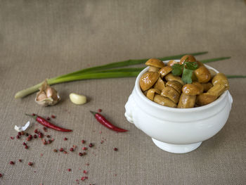 Salted mushrooms in bowl by spices on table
