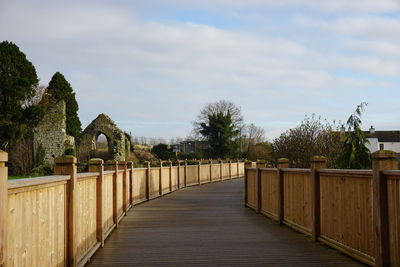 Footpath amidst trees and buildings against sky