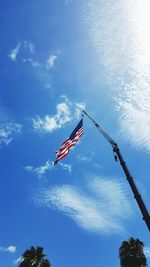 Low angle view of american flag hanging from crane against sky