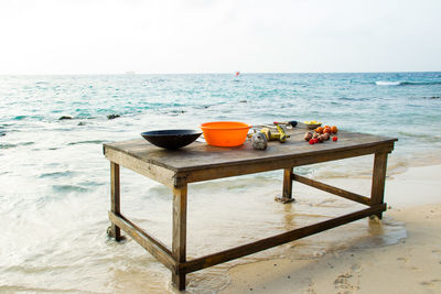 Containers with fruits and vegetables on table at beach