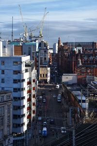 High angle view of cranes in city against sky