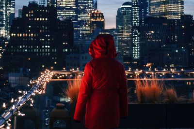 Rear view of man standing in city at night