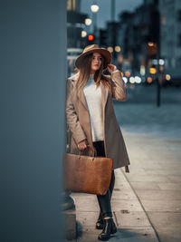 Woman holding umbrella standing in city