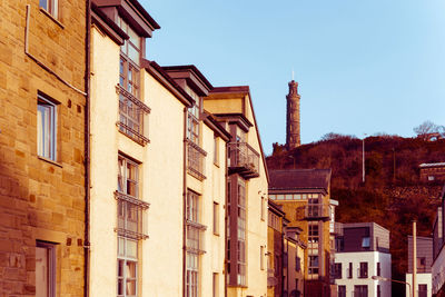 Low angle view of residential buildings in city by mountain against sky