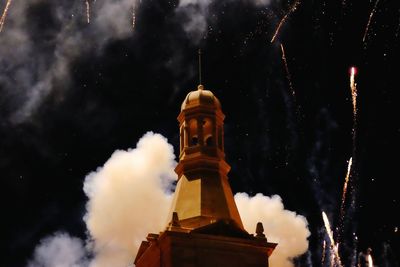 Low angle view of illuminated building against cloudy sky