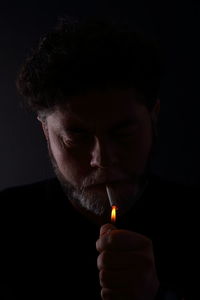 Close-up of man igniting cigarette against black background