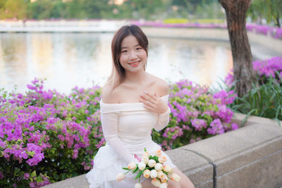 Portrait of young woman standing by plants