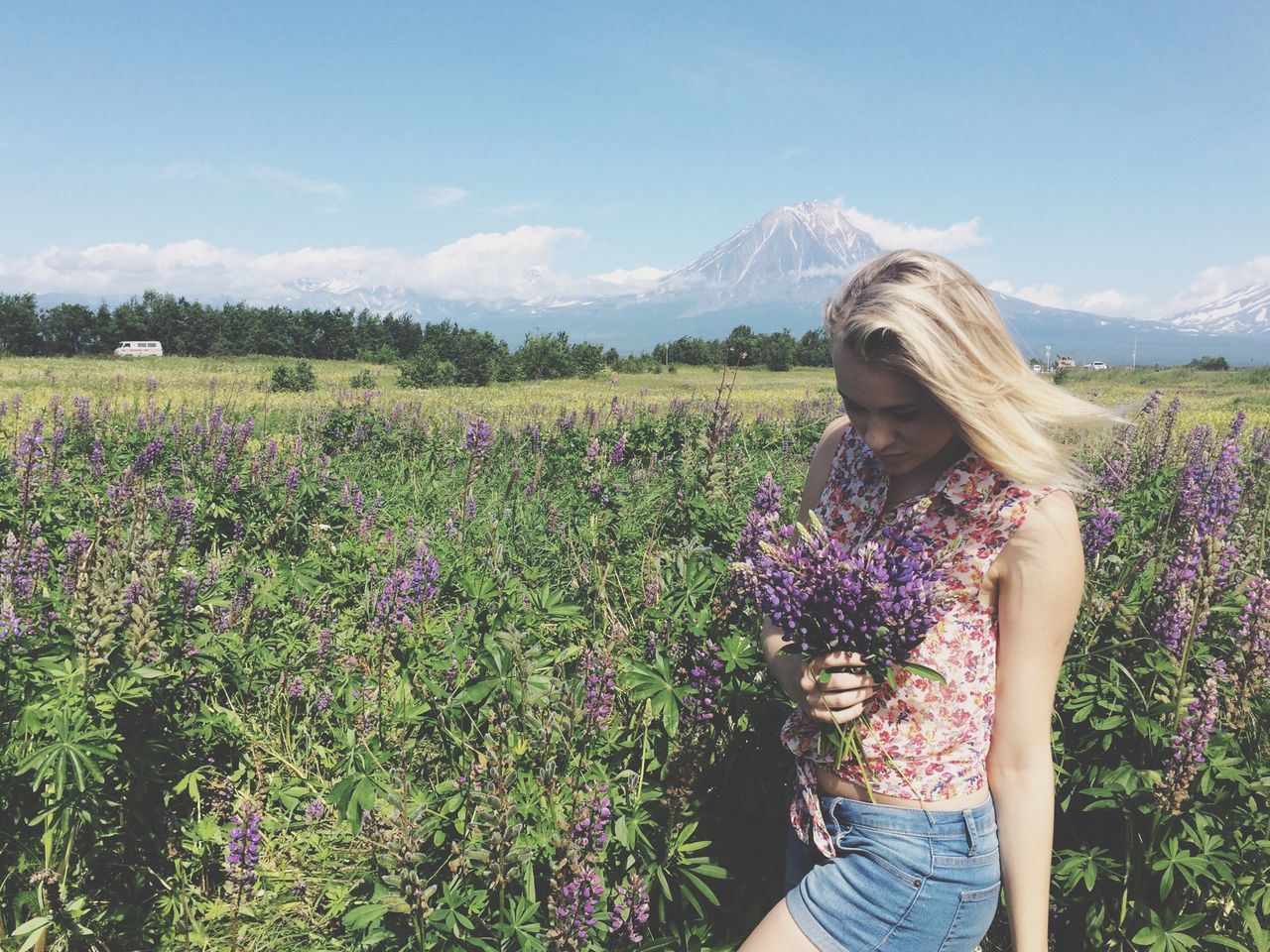 lifestyles, leisure activity, field, sky, beauty in nature, young women, landscape, nature, young adult, flower, tranquility, mountain, grass, casual clothing, tranquil scene, standing, scenics, plant