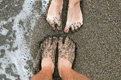 Low section of women standing at beach 