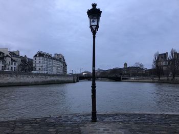 Street light by river against buildings in city