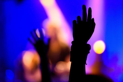 Silhouette of hands raised at a concert