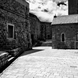 Footpath amidst old buildings against sky