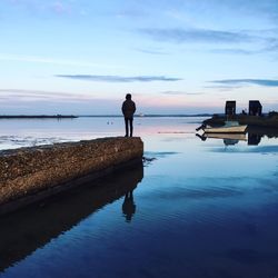 Rear view of man standing on beach against sky