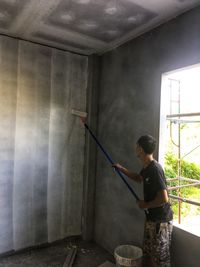 Side view of a man working on wall