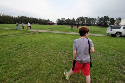 Rear view of boy walking on playing field
