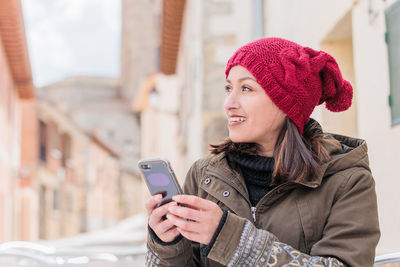 Young woman looking away while holding mobile