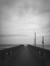 Pier on sea against cloudy sky