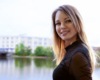 Portrait of young woman looking away against sky