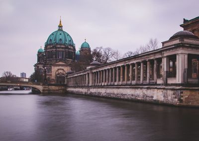 View of building by river against sky in city