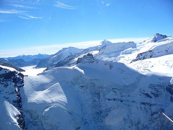 Scenic view of snowcapped mountains against blue sky