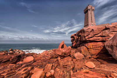 Men-ruz lighthouse in bretagne, france with scenic view of red cliffs agains blue sky