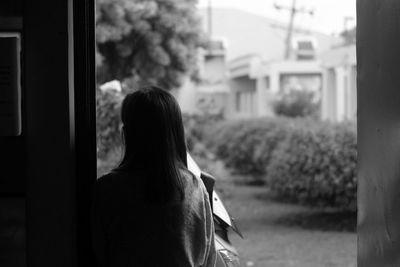 Rear view of man standing by window