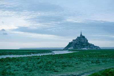 View of building by sea against cloudy sky