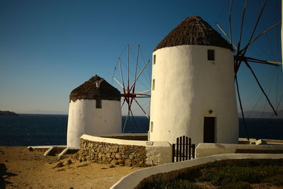 Lighthouse by sea against clear sky