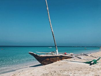 Sailboat moored on beach against clear sky