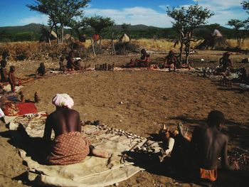 People sitting on field against sky