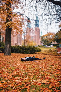 Young woman lying down in park during autumn