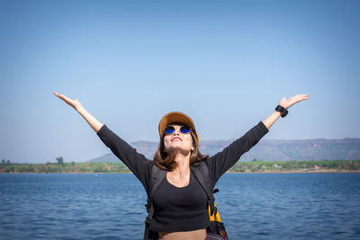 Portrait of young woman standing in water against sky