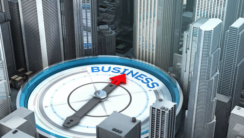 Digital composite image of navigational compass with business text and cityscape