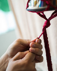 Close-up of hand weaving macramé hanging planter.