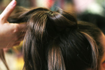 Cropped image of hairdresser hands making hair bun of woman