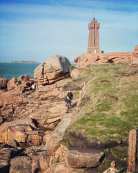 People on rock against sky