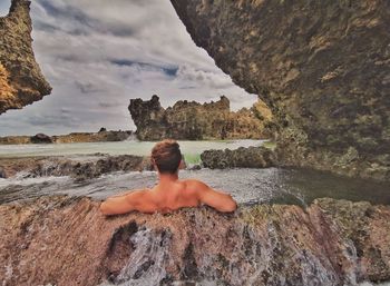 Rear view of shirtless man looking at sea