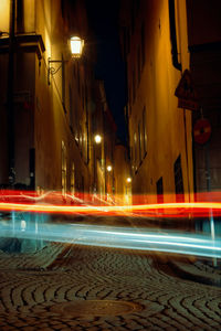 Light trails on street amidst buildings at night