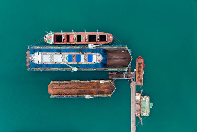 Oil tank ship repairing and maintenance on shipyard dock in sea aerial top view from drone