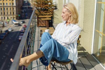 Side view of woman looking at man sitting on railing