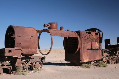 Abandoned train at desert against blue sky