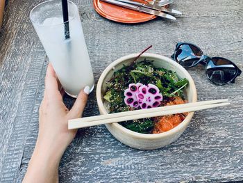 Directly above shot of hand holding drink on table