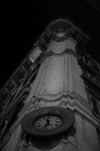 Low angle view of clock tower amidst buildings in city at night