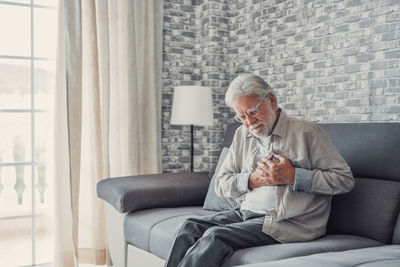 Side view of woman sitting on sofa at home