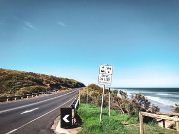 Road sign against clear blue sky