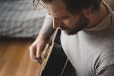 Side view of young man playing guitar